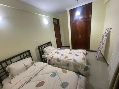 a bedroom with two beds and a door at Arusha Serenity Apartment in Arusha