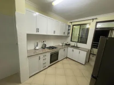 a white kitchen with white cabinets and a window at Arusha Serenity Apartment in Arusha