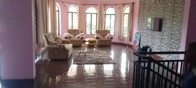 a living room with couches and chairs and windows at Sauda Homestay in Arusha
