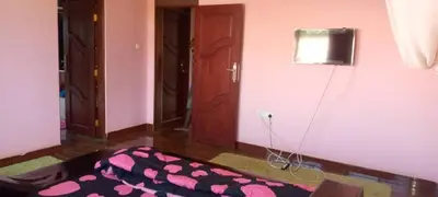 a room with a bed and a television on a wall at Sauda Homestay in Arusha