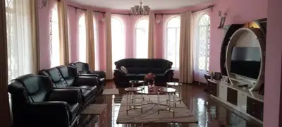 a living room with black leather chairs and a tv at Sauda Homestay in Arusha