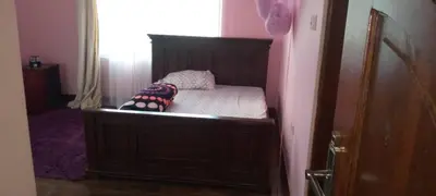 a small bedroom with a bed with a wooden headboard at Sauda Homestay in Arusha
