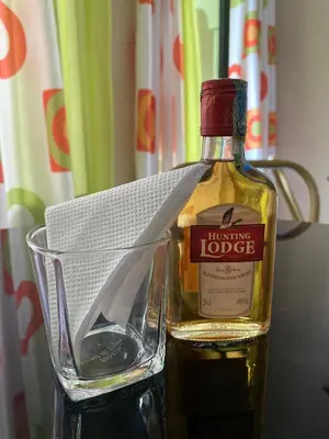 a bottle of whisky sitting on a table next to a glass at Kili Spring Hotel in Arusha