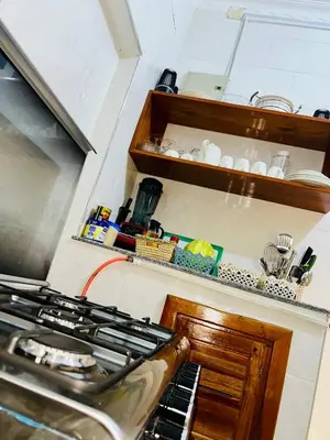 a kitchen with a stove and a shelf with dishes at The Dawn cottage in Moshi