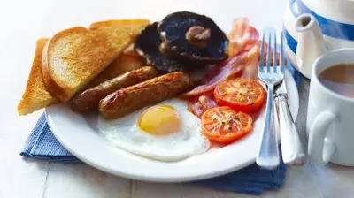 a plate of breakfast food with eggs bacon tomatoes and toast at The Dawn cottage in Moshi