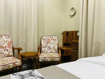 a bedroom with two chairs and a bed at The Dawn cottage in Moshi