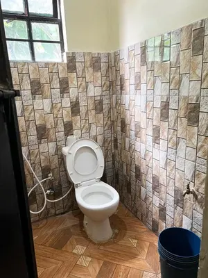 a bathroom with a toilet and a tiled wall at 'La Maison' 2 bedroom house in Arusha in Arusha