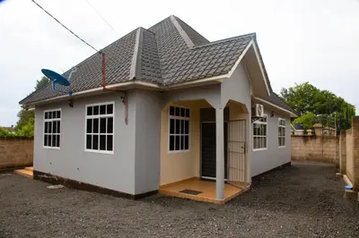 a small white house with a pitched roof at Velam Home Stay in Arusha