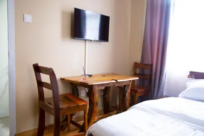 a room with a table with chairs and a tv on the wall at Velam Home Stay in Arusha