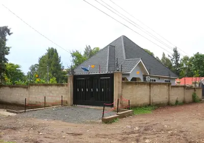 a building with a black garage with a fence at Velam Home Stay in Arusha