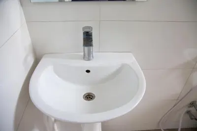 a bathroom with a white sink with a fosset at Velam Home Stay in Arusha