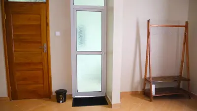 an empty room with a glass door and a chair at Velam Home Stay in Arusha