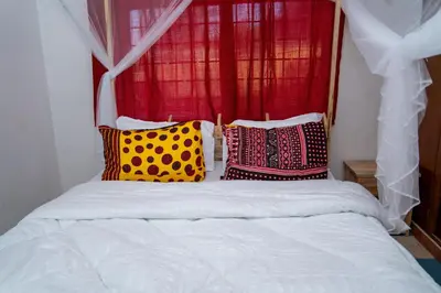 a bed with colorful pillows in front of a window at Kwetu Hostel in Arusha