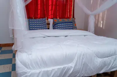 a bedroom with a white bed with blue and red curtains at Kwetu Hostel in Arusha