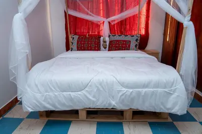 a bedroom with a white bed with red curtains at Kwetu Hostel in Arusha