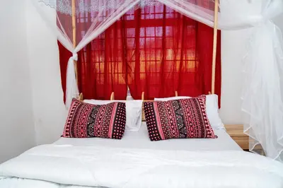 a bed with red and white pillows on it at Kwetu Hostel in Arusha