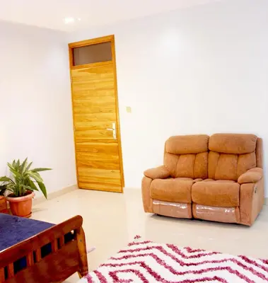 a living room with a brown chair and a rug at Asante Karibu House in Arusha