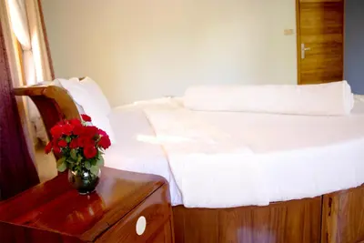 a bedroom with a bed with a vase of flowers on a table at Asante Karibu House in Arusha