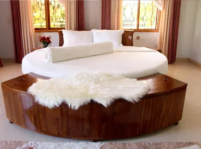 a large bed with a wooden frame with a white blanket at Asante Karibu House in Arusha