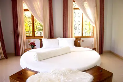 a bedroom with a large white bed with windows at Asante Karibu House in Arusha