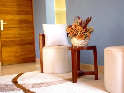 a vase of flowers sitting on a table next to a stool at Asante Karibu House in Arusha