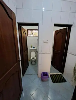 a bathroom with a toilet in a room with a door at Villa Jane in Arusha in Arusha