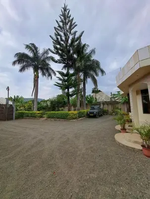 a parking lot in front of a house with palm trees at Villa Jane in Arusha in Arusha