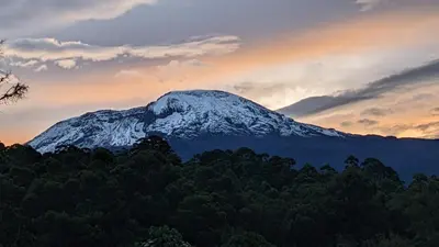 a mountain covered in snow with a sunset in the background at Barangata collections in Barangata