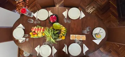 a wooden table with white plates and fruit on it at Barazani Garden House in Moshi