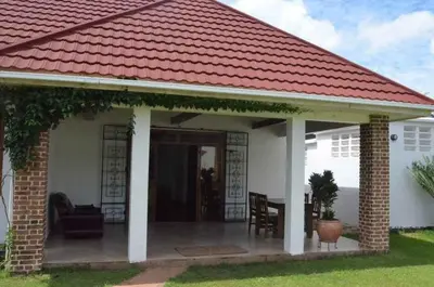 a small white house with a red roof at Barazani Garden House in Moshi