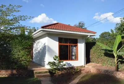 a small white house with a red roof at Barazani Garden House in Moshi