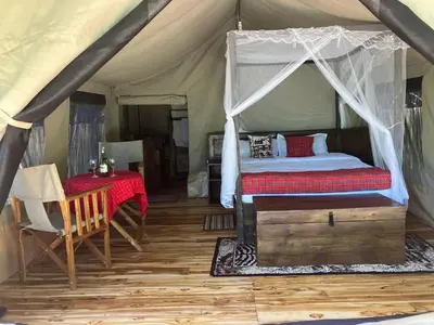 a bedroom with a tent with a bed and a table at Keremasi Camp Lake Natron in Mtowabaga