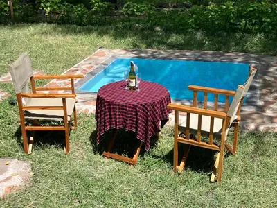 two chairs and a table with a bottle of wine on it next to a pool at Keremasi Camp Lake Natron in Mtowabaga