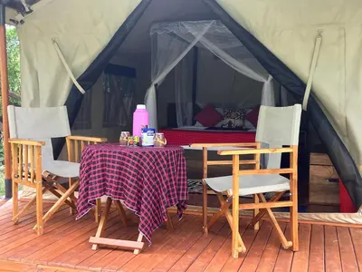 a tent with a table and chairs on a deck at Keremasi Camp Lake Natron in Mtowabaga