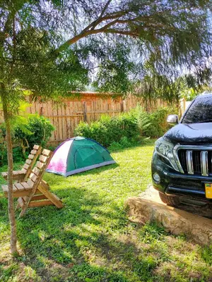 a tent and a chair in a yard next to a car at Bright Michelle Homestay in Lushoto