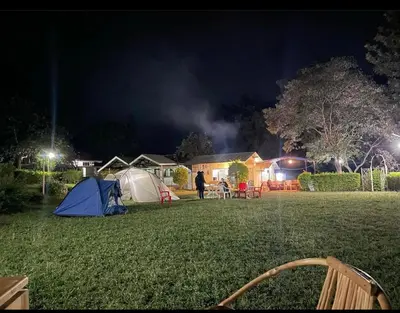 a person standing in a field with tents at night at Jibambe campsite in Moshi