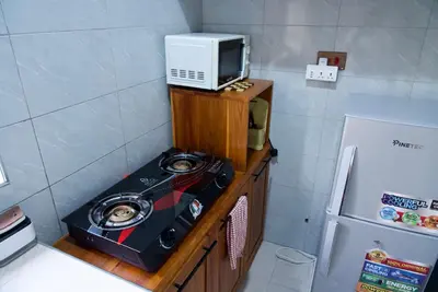 a microwave sitting on top of a wooden stand next to a refrigerator at Nyumbani Nyumbani in Arusha