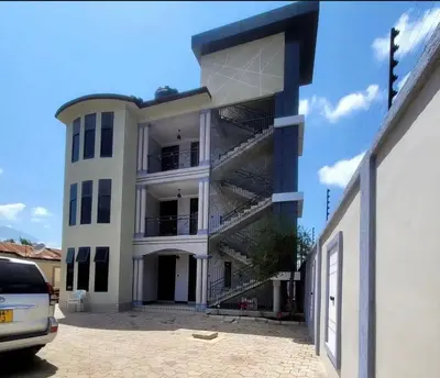 a large white building with a staircase in front of it at QD Apartment in Arusha