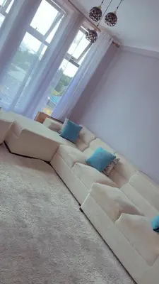 a living room with a large couch with blue pillows at QD Apartment in Arusha
