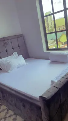 a bed in a room with a couch and a window at QD Apartment in Arusha