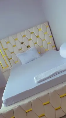 a bed with a yellow and white bed frame at QD Apartment in Arusha