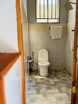 a small bathroom with a toilet and a window at leo apartment in Arusha