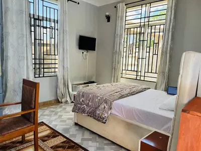 a bedroom with a bed and two windows at leo apartment in Arusha