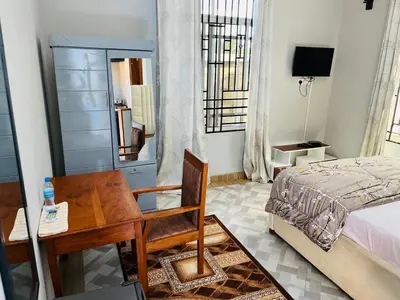 a bedroom with a desk and a bed and a table at leo apartment in Arusha