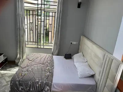 a bed in a room with a large window at leo apartment in Arusha
