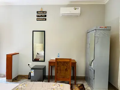 a room with a refrigerator and a table and a mirror at leo apartment in Arusha