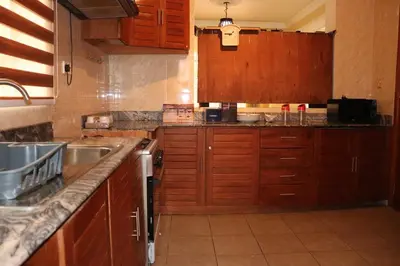 a kitchen with wooden cabinets and a sink at Madalina's Appartment in Arusha