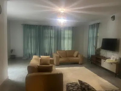 a living room with a couch and a tv at Lively Cottages Momella,Main House in Usa River