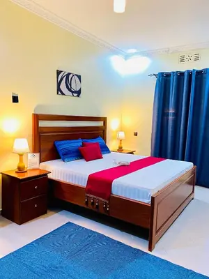 a bedroom with a bed with red and blue pillows at Amellie's Home Safari in Nkunjila