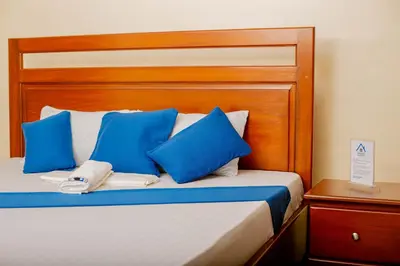 a bed with blue pillows and a wooden headboard at Amellie's Home Safari in Nkunjila